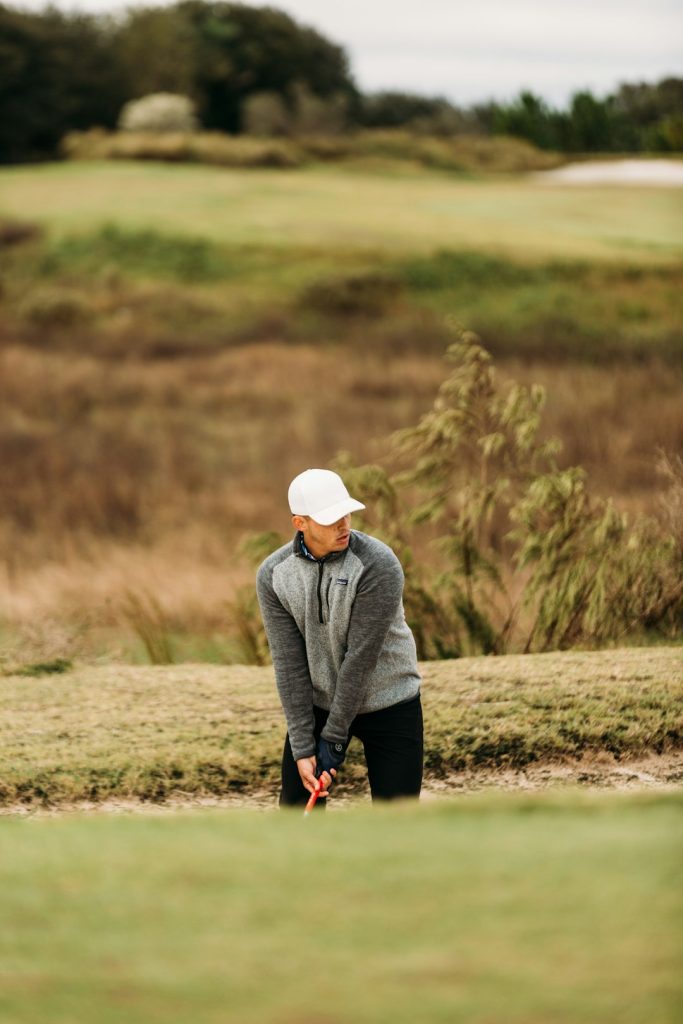 Golfer in bunker looking over left shoulder.