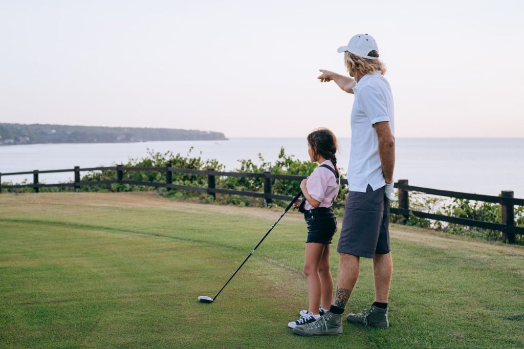 A father and daughter playing golf near the ocean with beautiful views.
